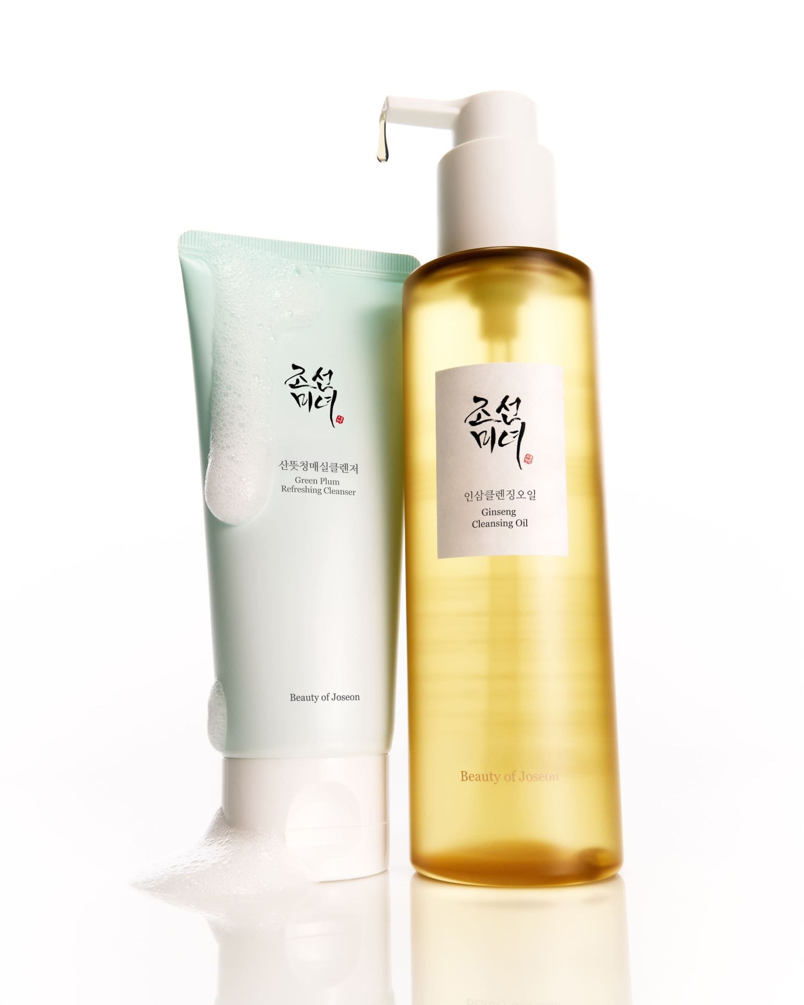 Beauty of Joseon Green Plum Off-White Cleansing Cleanser tube next to Beauty of Joseon Glowing Cleansing Oil in a clear bottle with a white pump dispenser, on a white background.