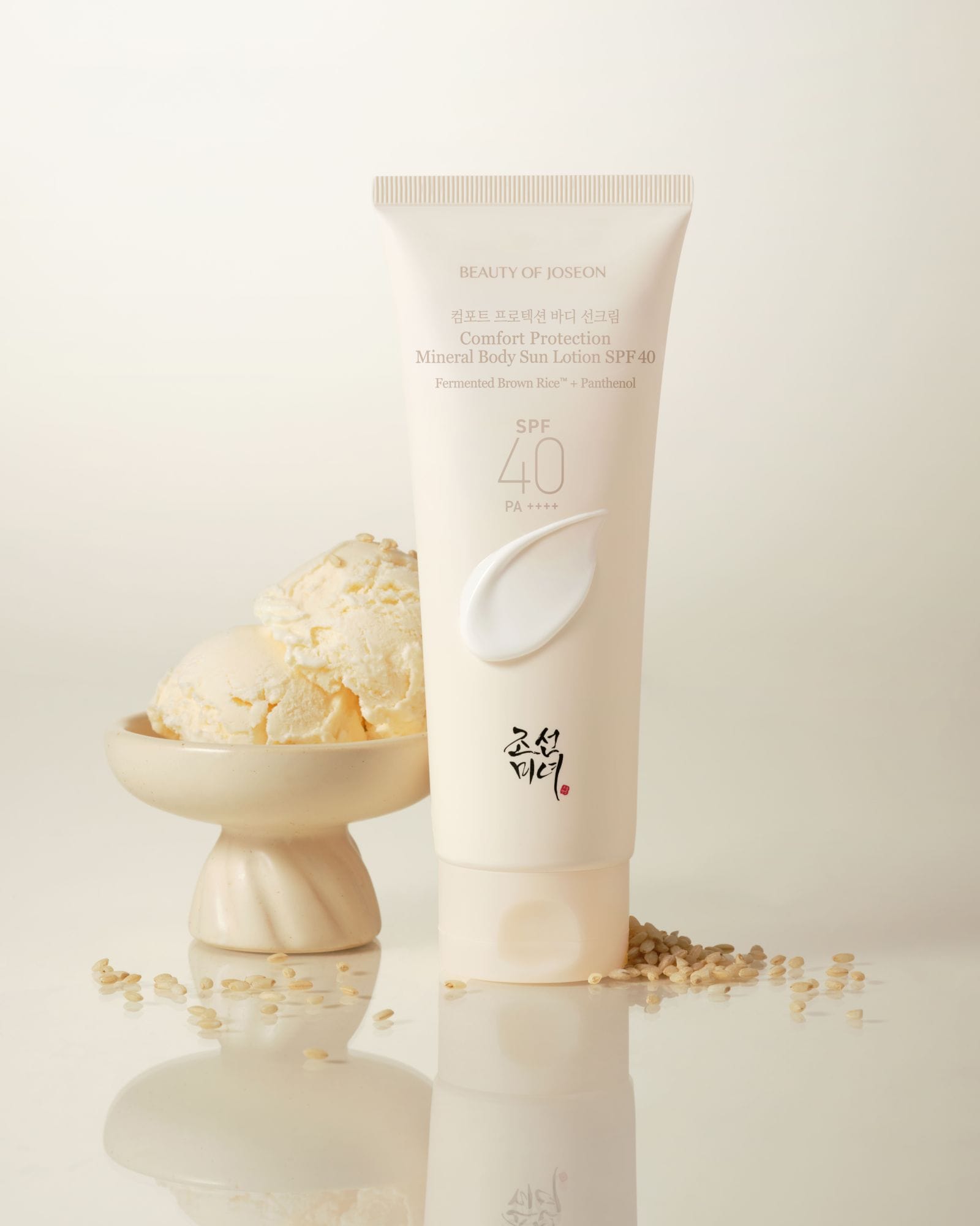 A tube of Comfort Protection Mineral Body Sun Lotion with decorative elements such as ice-cream and ingredient of the product on a light background. SPF 40