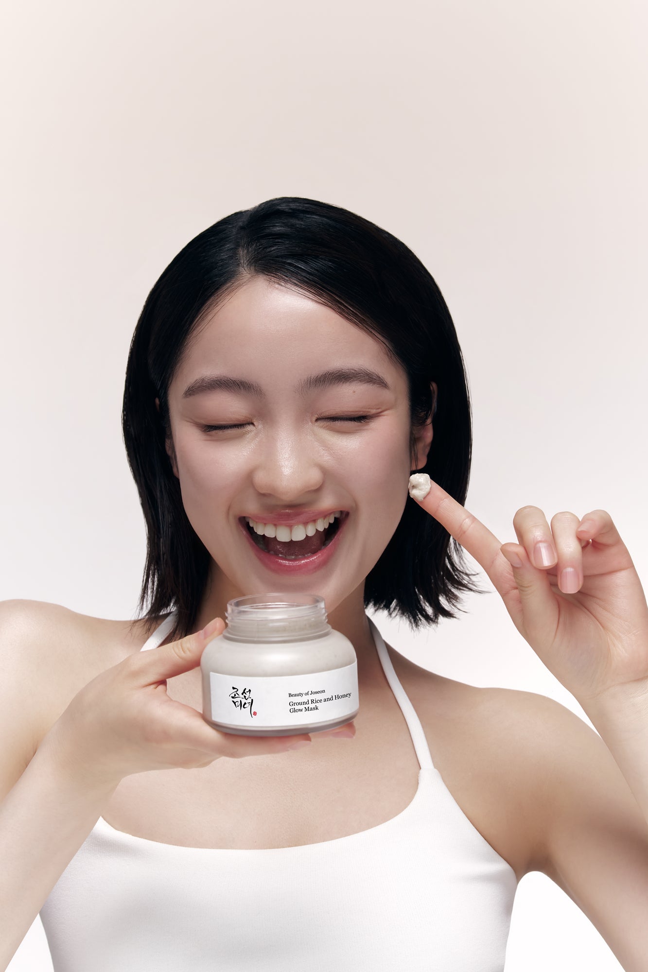 a woman smiling and holding a jar of cream